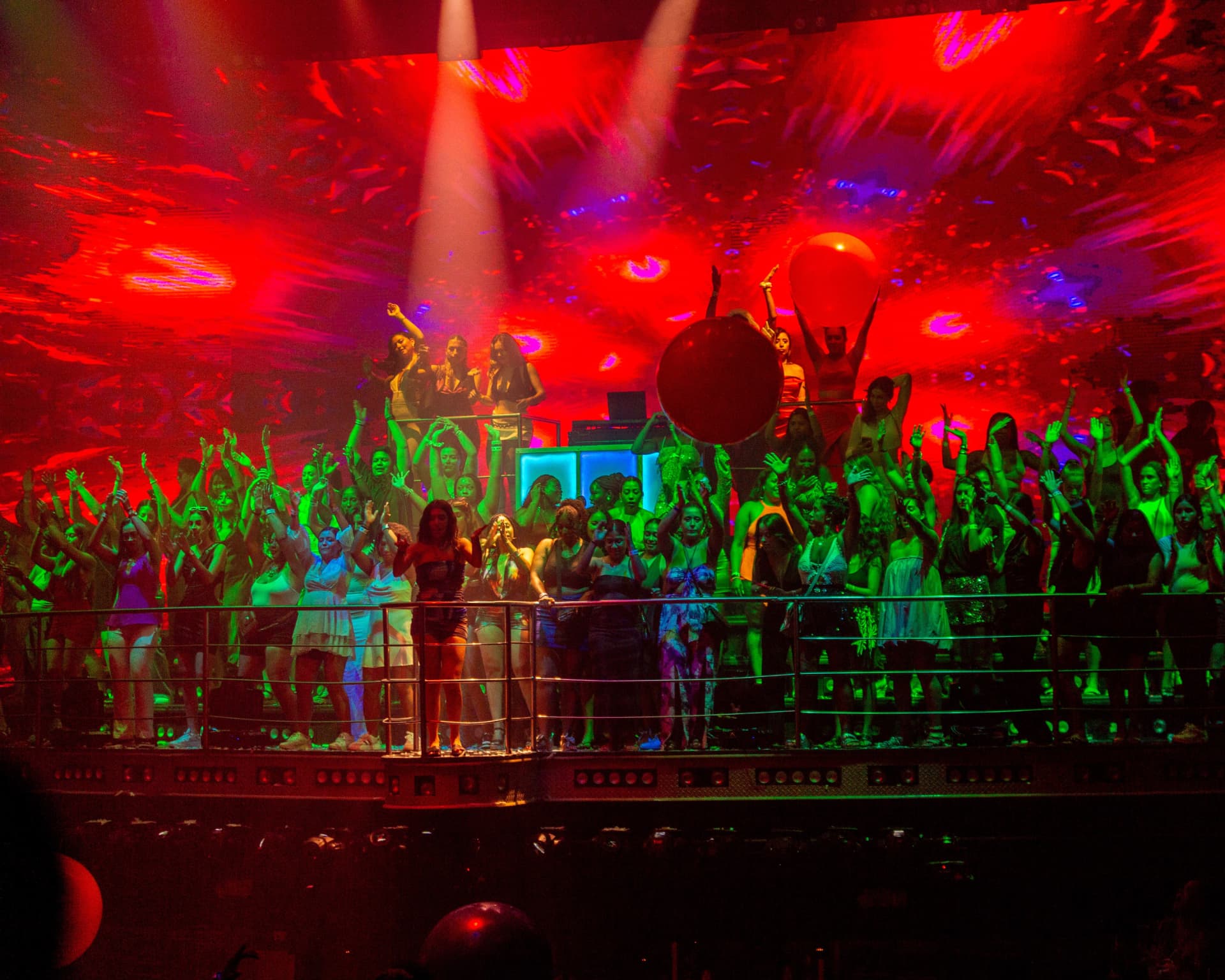 Público dançando no palco sob luzes vermelhas